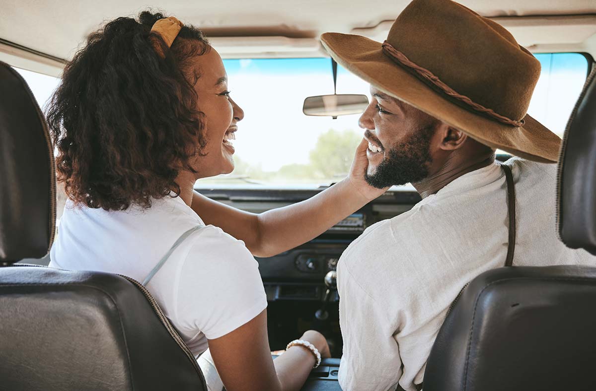 Happy African-American couple embracing the benefits of couples coaching, enjoying a road trip together, fostering connection and growth.