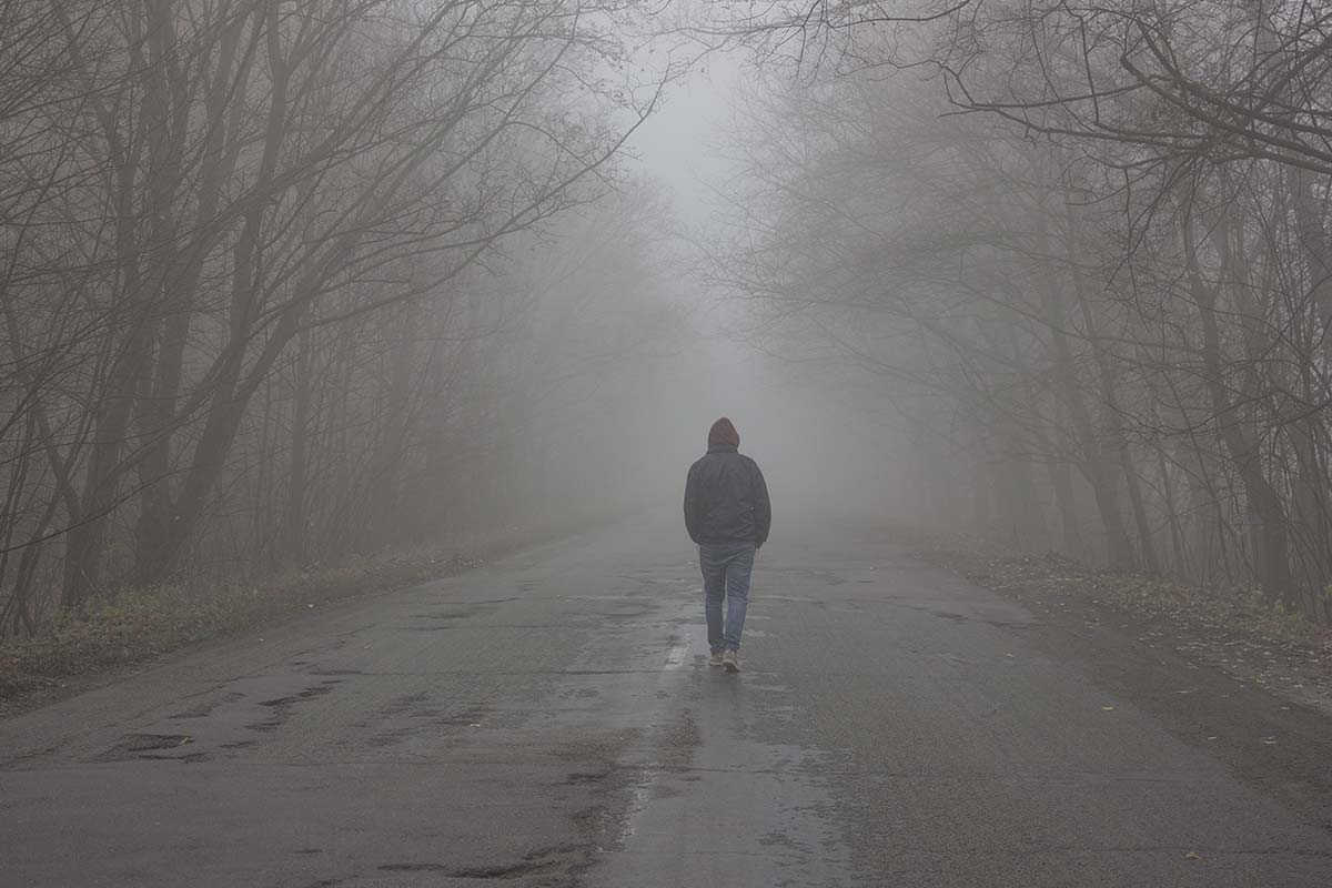 A man walking on a foggy road, signifying the process of conscious uncoupling